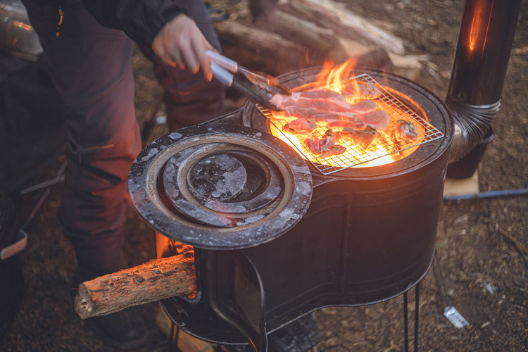Midsection of man preparing food on camp barbecue grill