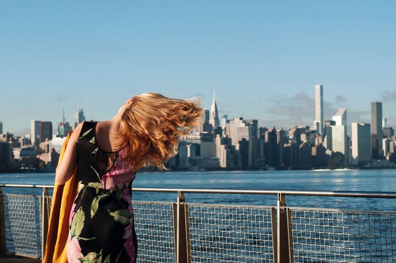 Rear view of woman standing by railing against clear sky