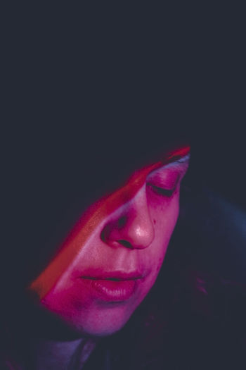 close-up of young woman with eyes closed against black background