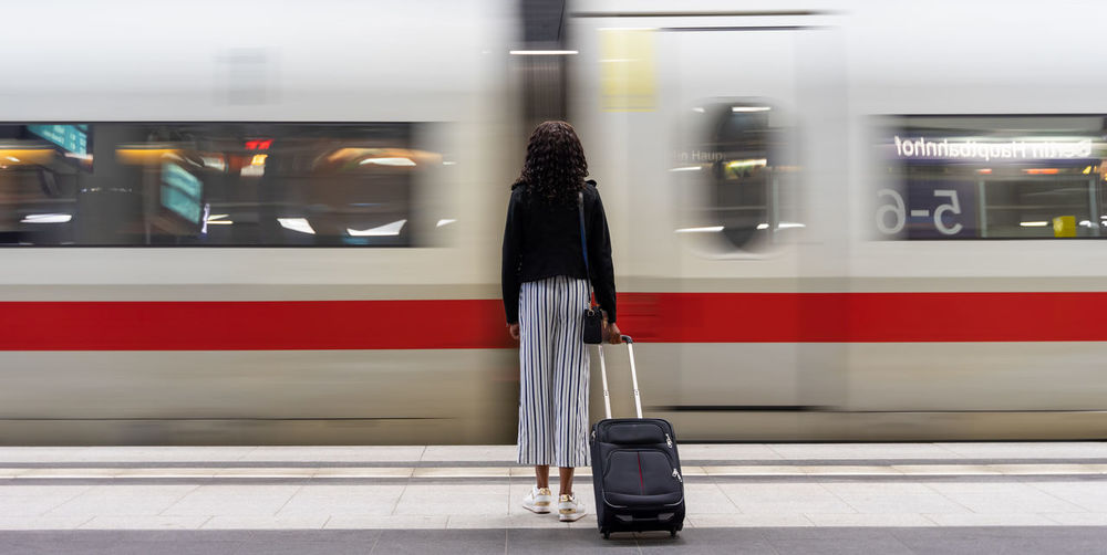 Rear view of woman standing against moving train 