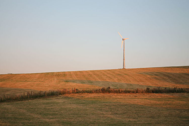 Windmill on field against clear sky