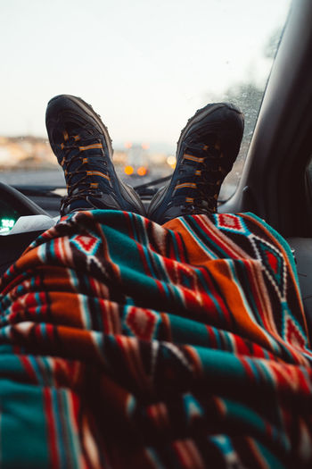Crop legs of tourist covered with blanket into a car