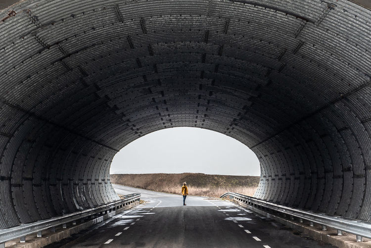 Full length of woman standing on road under tunnel