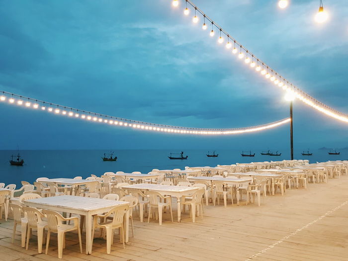 The romantic evening dining place decorated with the warm lamps and sea view