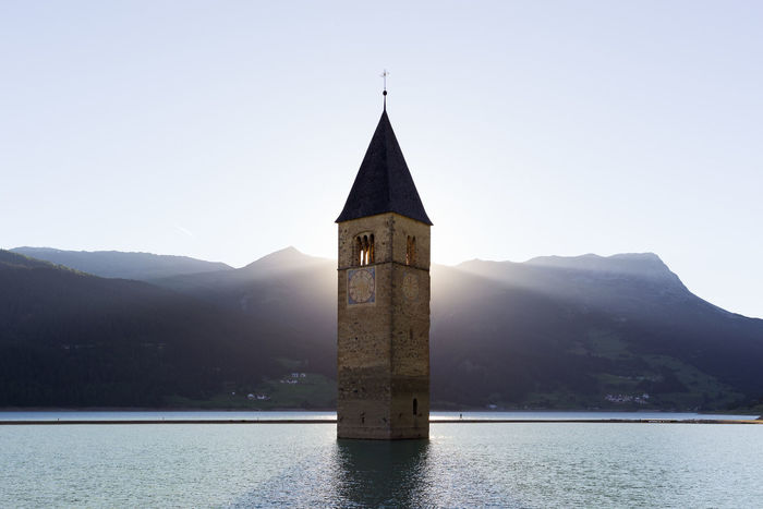 Bell tower in sea against mountains