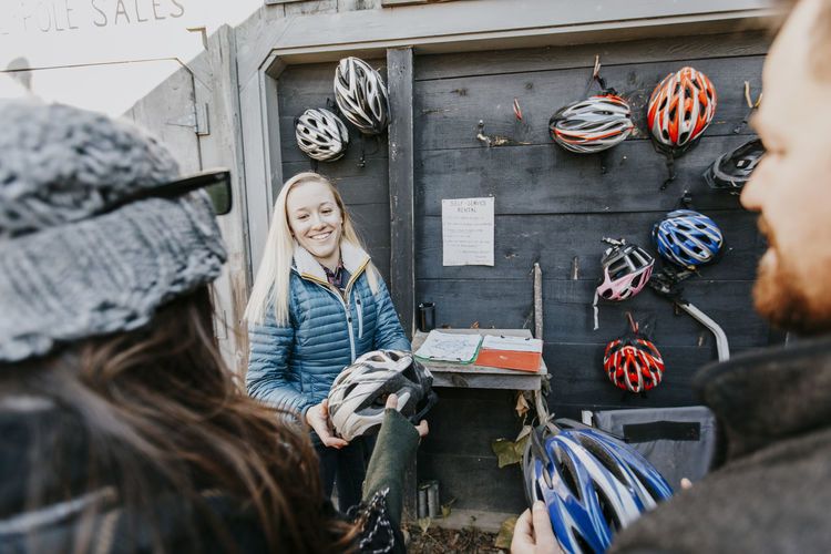 A young woman passes out bike helmets at a bike shop
