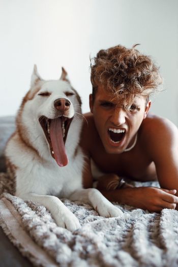 Portrait of angry young man shouting while lying by dog at home