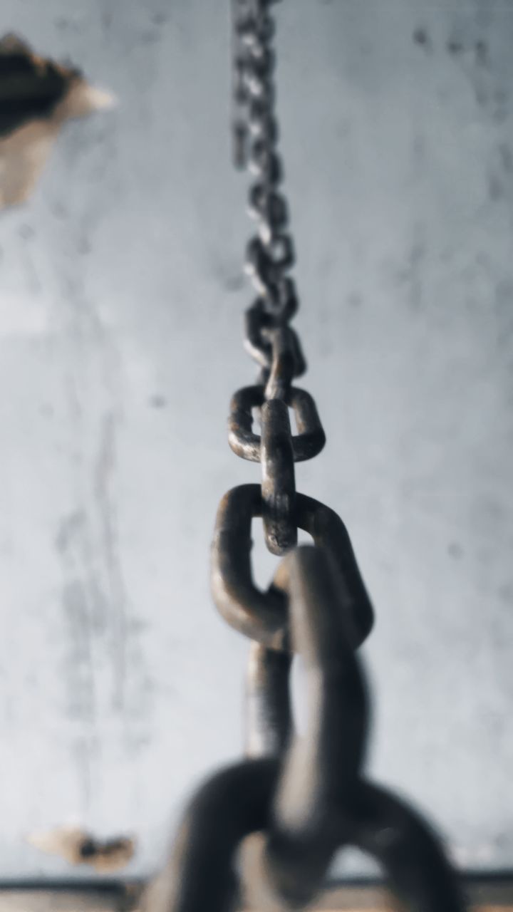 CLOSE-UP OF CHAIN HANGING ON METAL WALL