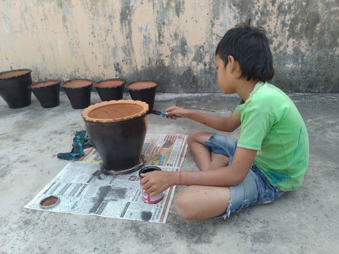 Boy painting the flower pot