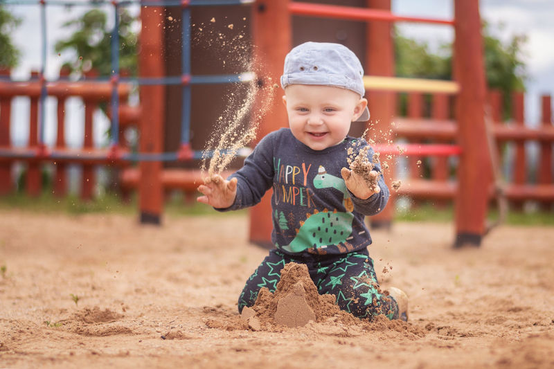 Cute baby boy playing with sand in playground