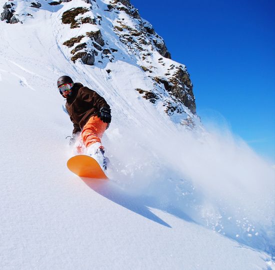 Low angle view of man snowboarding on snowcapped mountain