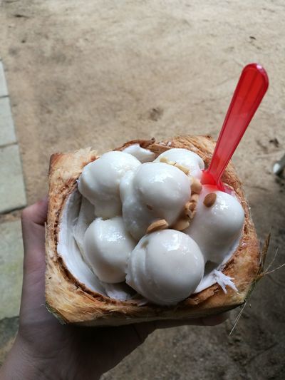 Cropped hand of person holding ice creams in coconut
