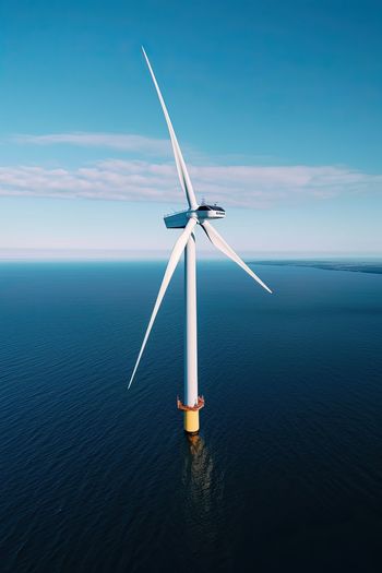 Drone aerial view of windmill in the ocean in a sunny day.ai generated