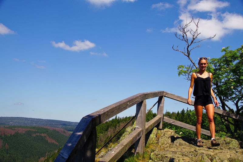 Woman walking at railing against blue sky