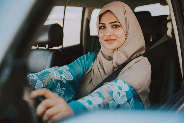 Portrait of smiling woman in hijab sitting in car