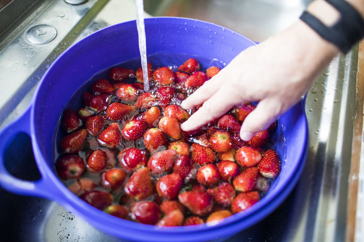 Washing fresh strawberries with water in the sink.