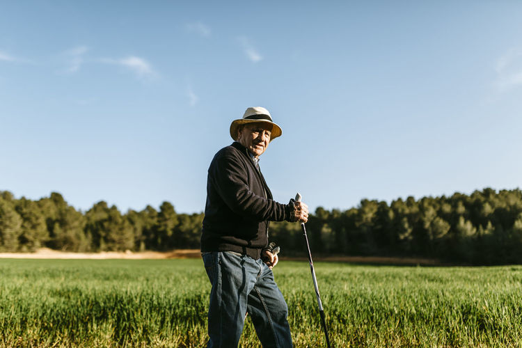 Spain, tarragona, senior man walking with sticks in the field