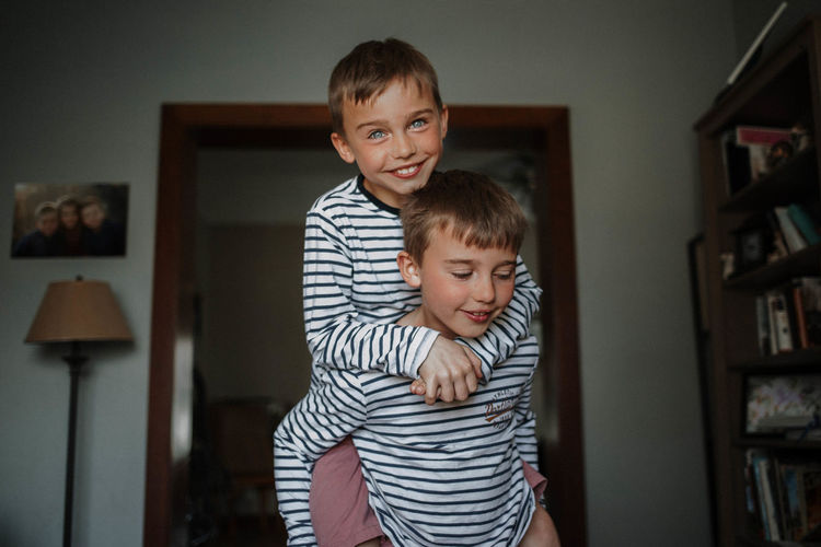 Portrait of cute boy carrying by brother at home