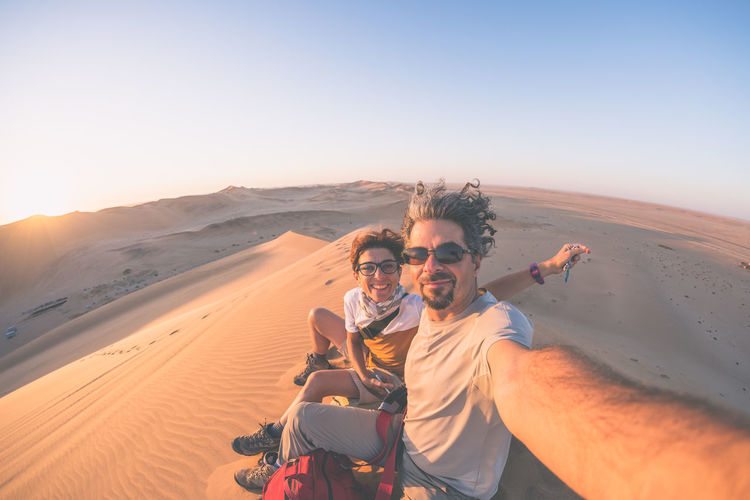 Portrait of couple in desert against clear sky