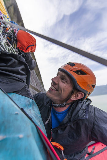 Climber smiling and looking up with climbing helmet to gear hanging