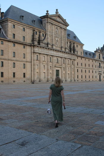 Rear view of woman walking on street against buildings in city