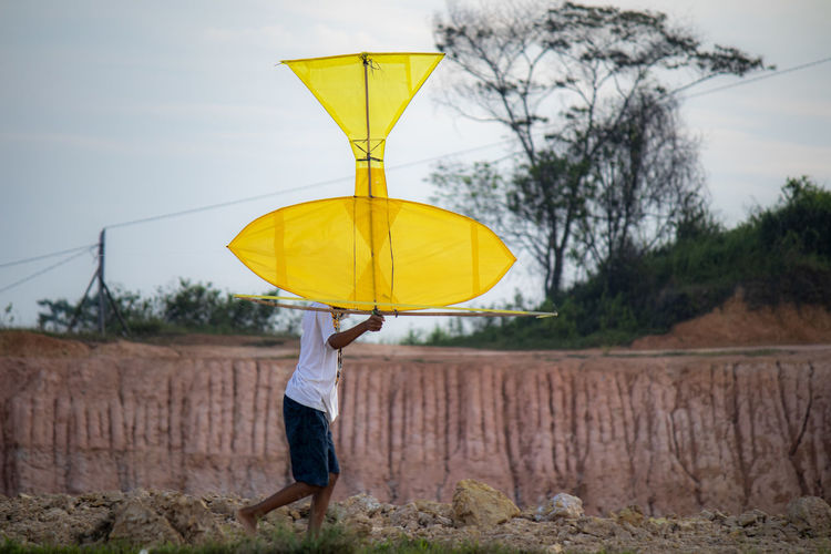 Woman standing by yellow umbrella during rainy season