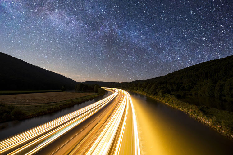 Light trails on road against sky at night