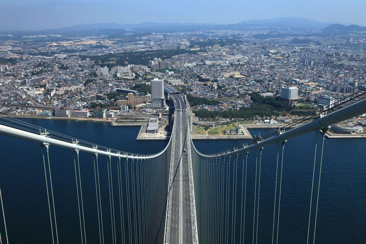 High angle view of suspension bridge over sea by cityscape