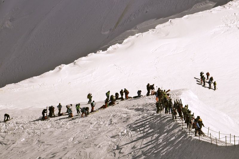 High angle view of people climbing on snowcapped mountain