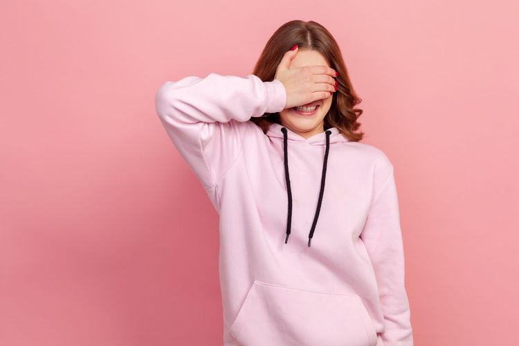 Full length of woman standing against pink background