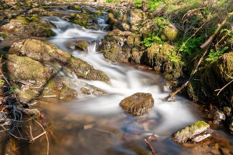 Long exposure of the weir water river flowing through the valley at robbers bridge in exmoor 