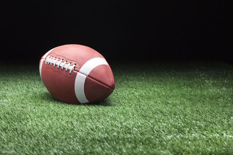 Close-up of red american football ball on green field