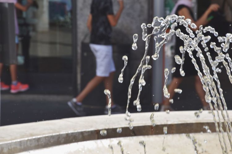 Close-up of fountain spraying water by people on street