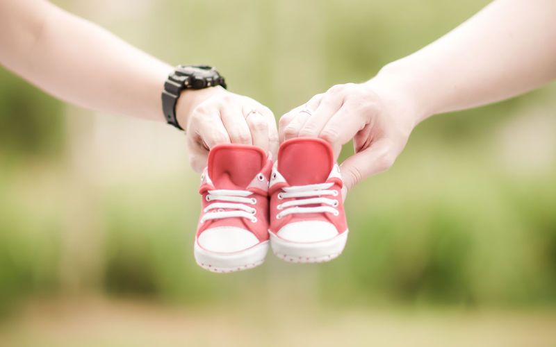 Cropped image of people holding baby booties