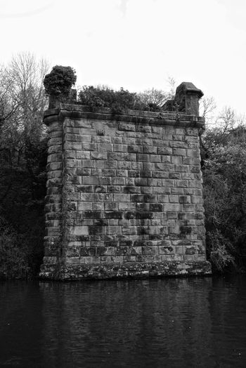 Old ruins by lake against sky
