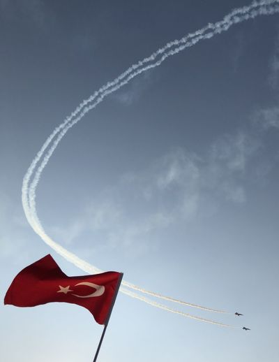 Low angle view fighter plane flying against flag in sky