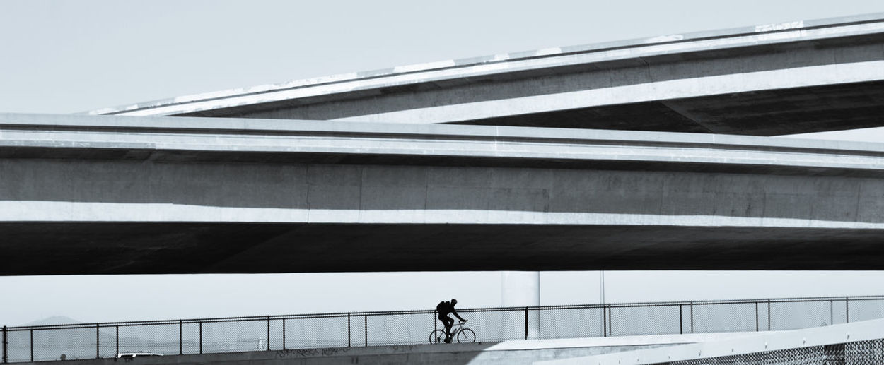 Low angle view of cyclist on bridge against sky