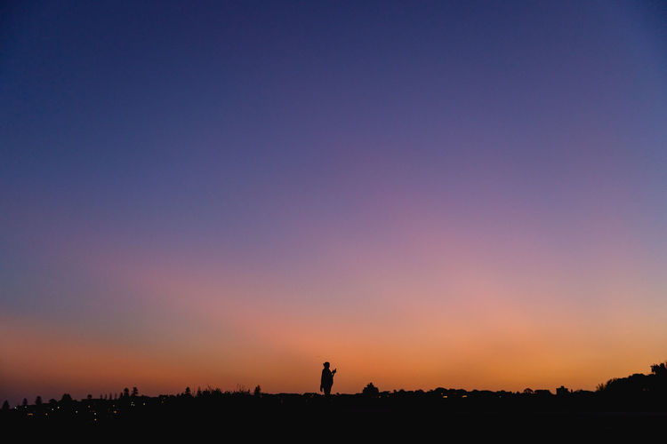 Silhouette of a person on field against clear sky during sunset