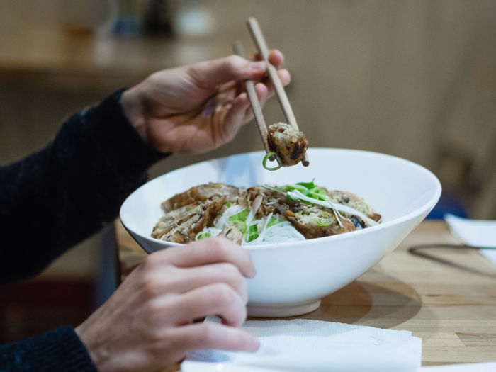 Midsection of person eating asian food with chopsticks