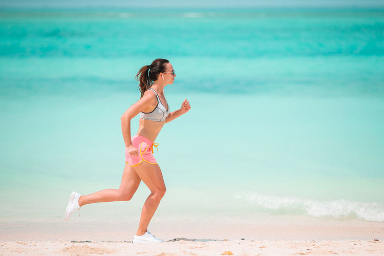 Side view of woman running on beach