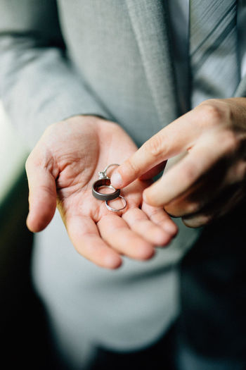 Midsection of well-dressed man holding finger rings