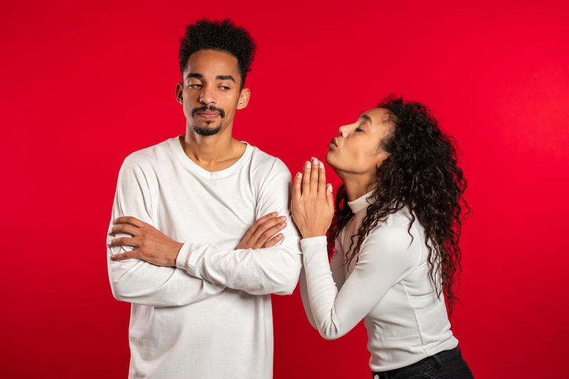 Young man and woman standing against red background