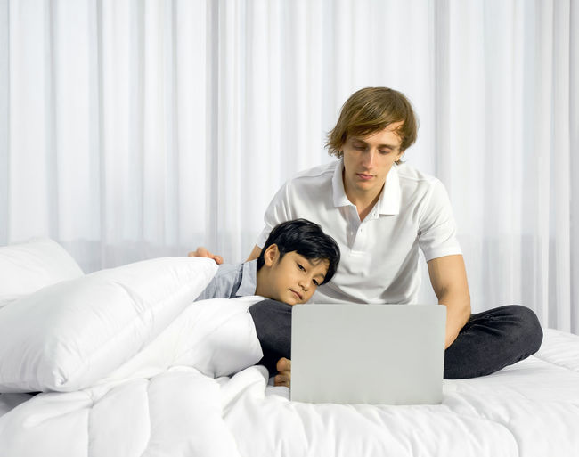 Young man using laptop on bed at home