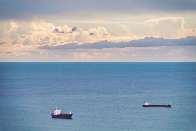 Scenic view of sea and container ships against sky