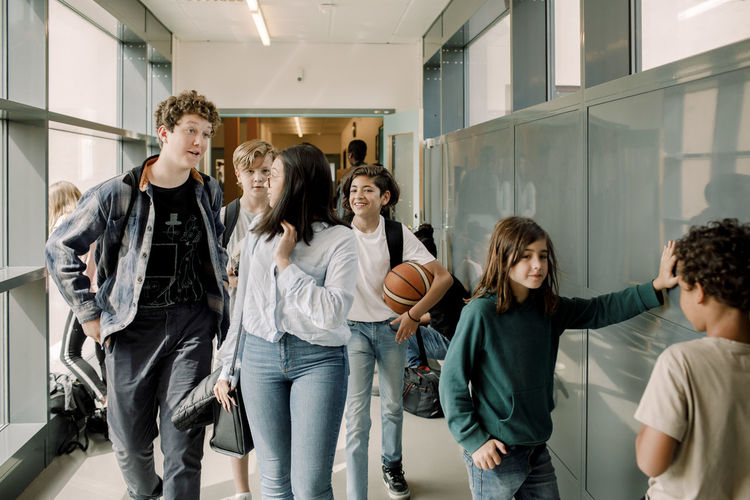 Male and female students talking in school corridor during break