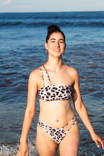 Portrait of smiling young woman standing at beach