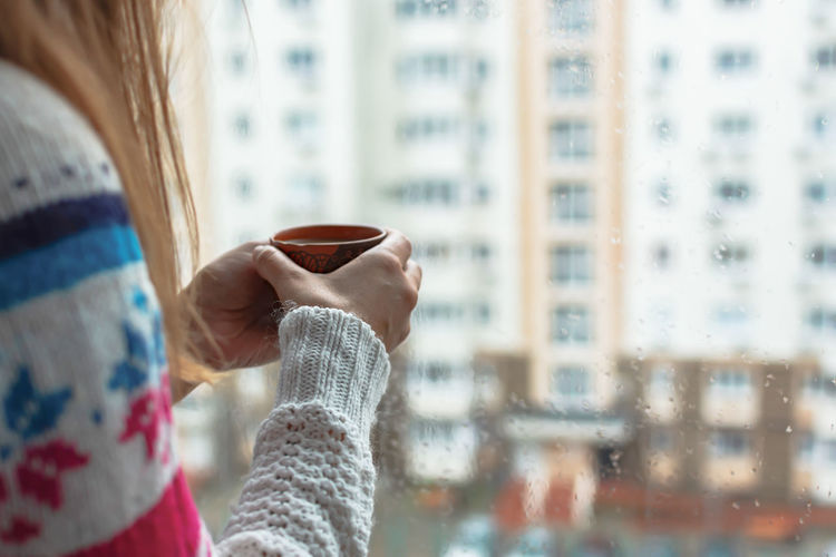 Midsection of woman holding coffee cup in city