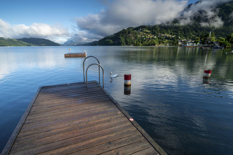 Scenic view over millstätter lake from a beach with jetty to mountains