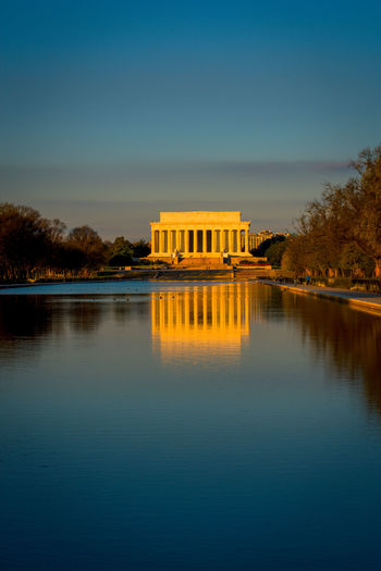 Lincoln memorial by lake against blue sky