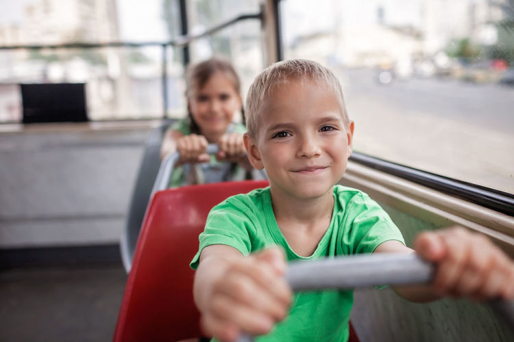 Kids ride in empty tram and look at the window with smile, public transportation, city tramway